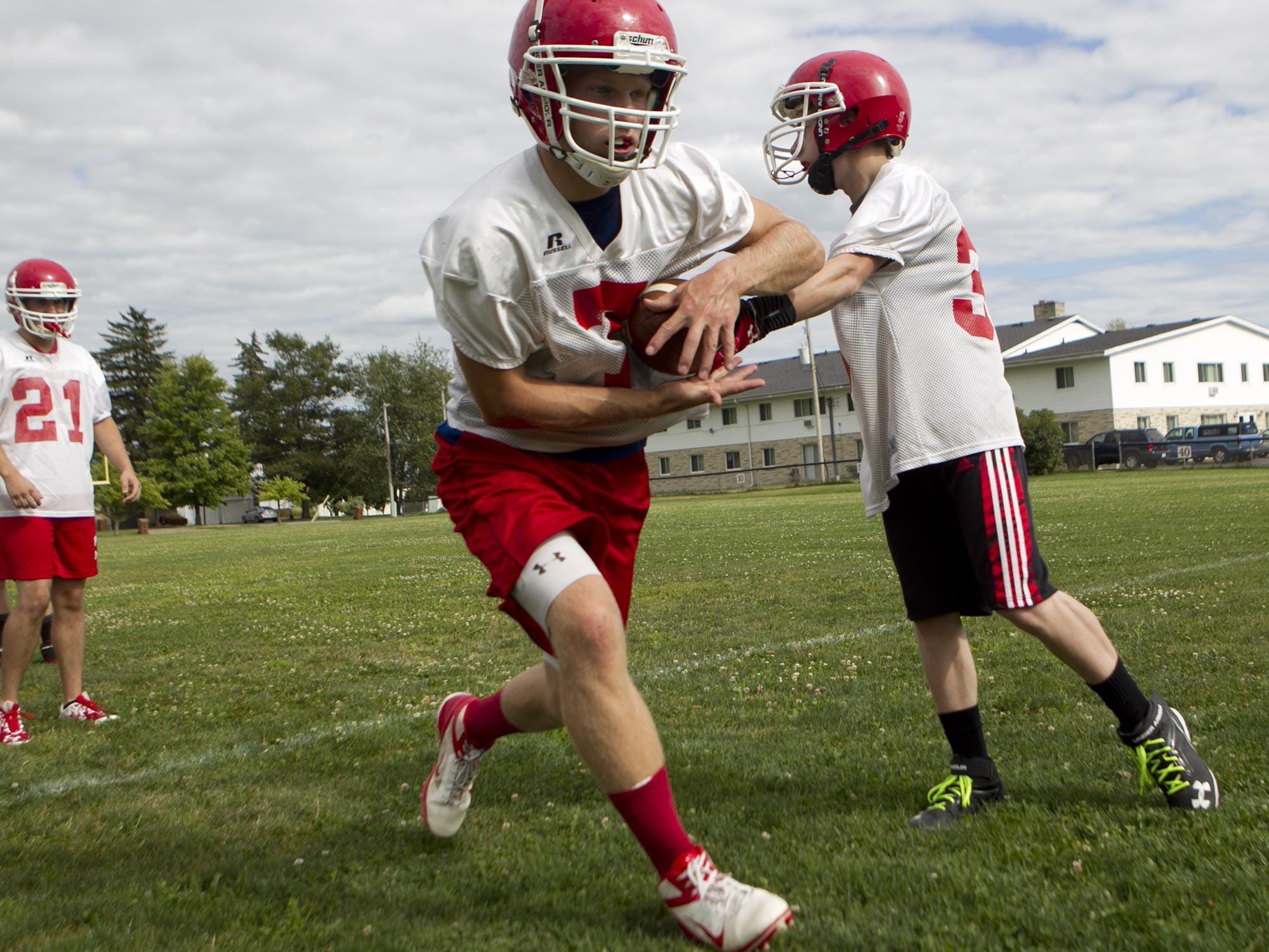 Pacelli football player Chris Shibilski, left, takes the hand off from Ben Lundgren, right, during the first day of football practice at Pacelli High School, Aug. 4.
