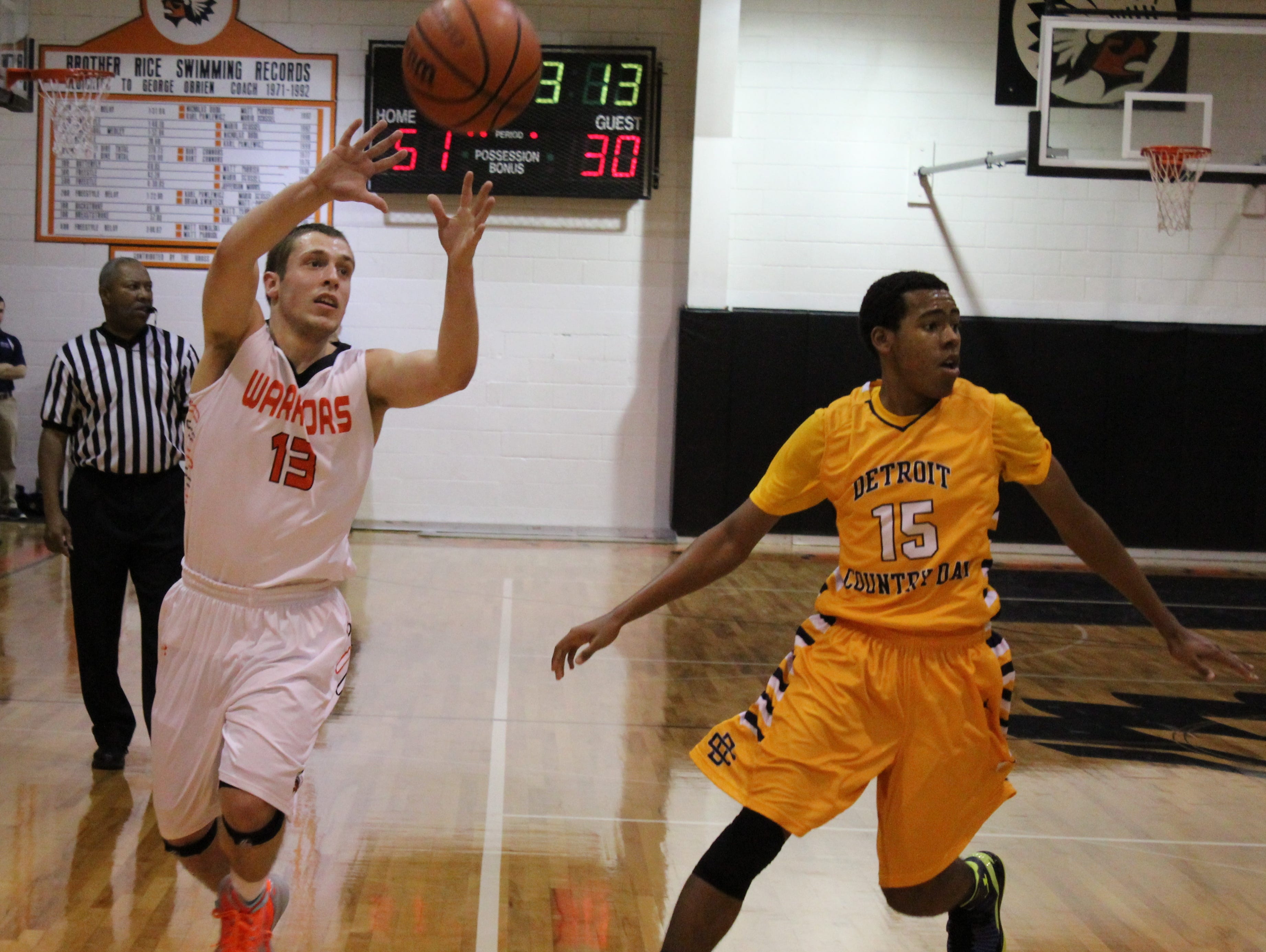 Brother Rice senior guard Dominic Downs (13) slips the ball past Country Day defender Devin Beach (15) in Friday’s game played at Rice. The Warriors won, 77-51.