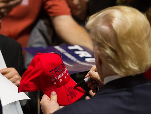 Trump signs a hat after speaking at a rally at the