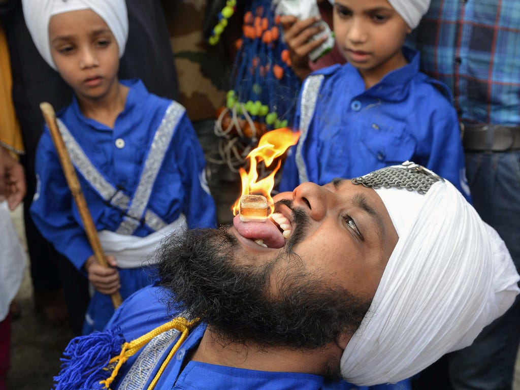 An Indian Nihang, a religious Sikh warrior, holds a flammable cube on his tongue during a religious procession to mark the 413rd anniversary of the installation of the Guru Granth Sahib at the Golden Temple in Amritsar on Aug. 22, 2017.
