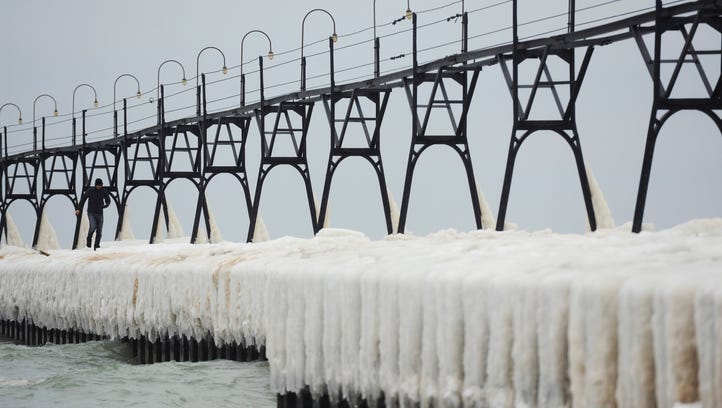 A man walks along the ice covered pier at the South