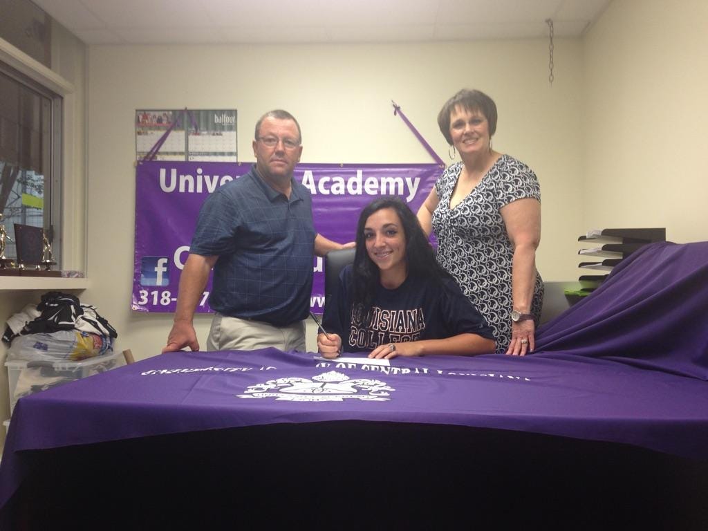 University Academy catcher Allie Davis (center) signs with Louisiana College as new softball coach Craig Whittington (left) and UA Director DeEtte Loyd look on.