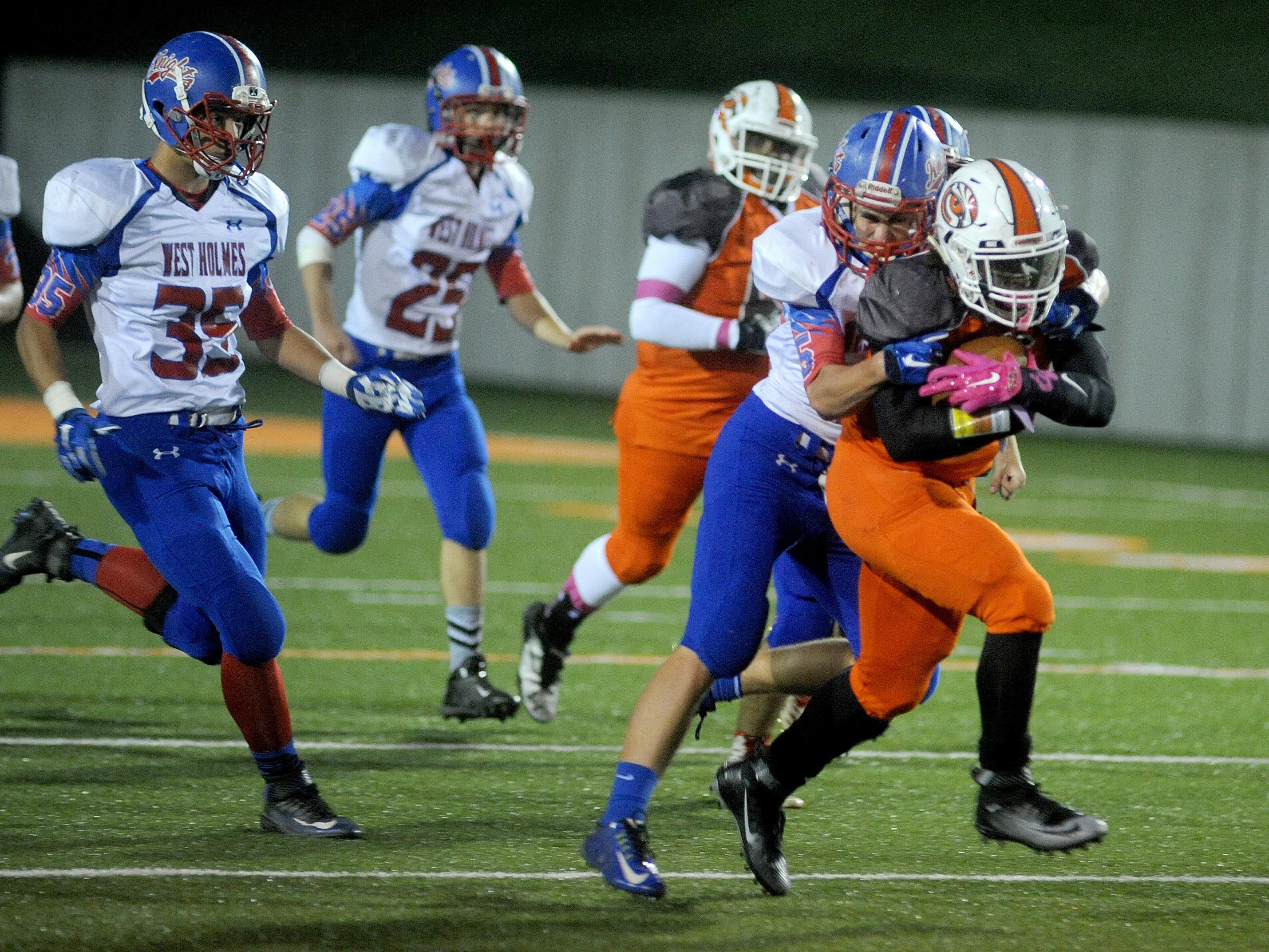 Connor Roach of West Holmes clutches on to Mansfield Senior's Tyquan Vickers after he picked up big yards on a long run Friday night at Arlin Field.