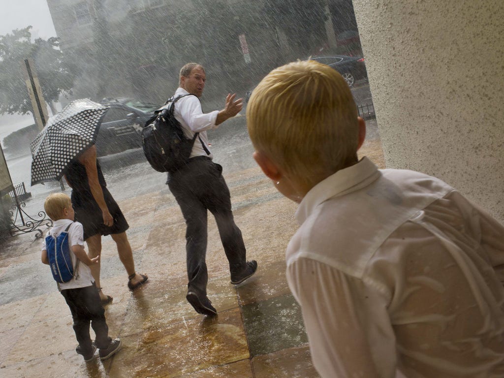 A father calls to his son as they run out to the curb to grab a taxi during a heavy rainstorm in Washington, D.C.