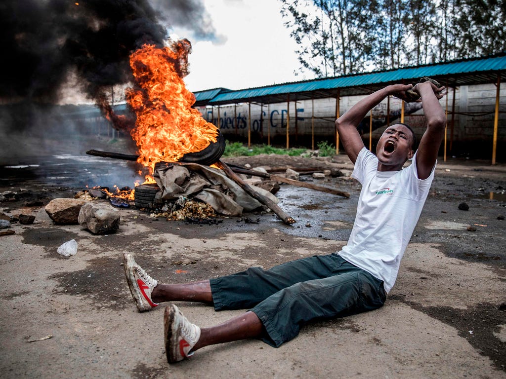 An opposition supporter reacts under the heavy rain in front of a burning barricade in Mathare district in Nairobi on Oct. 26, 2017, as a group of demonstrators blocked the road and tried to prevent voters from accessing a polling station during pres
