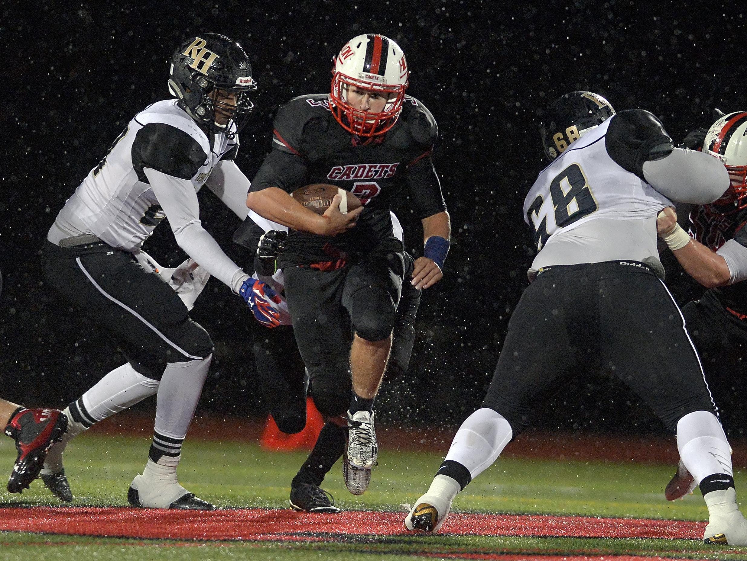 Hilton's Dillon Philmon, center, breaks through a hole in the line of scrimmage against Rush-Henrietta at Hilton High School on Oct. 16, 2015.