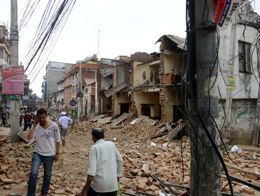Nepalese walk past collapsed buildings at Lalitpur,