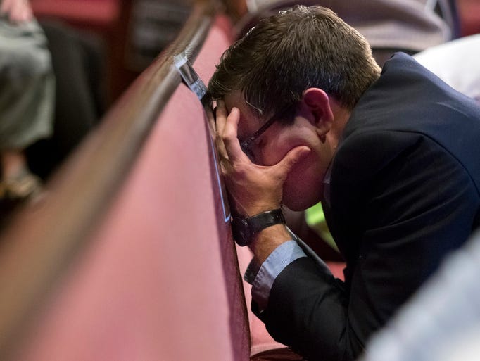 Chad Harris presses against a pew as he prays during
