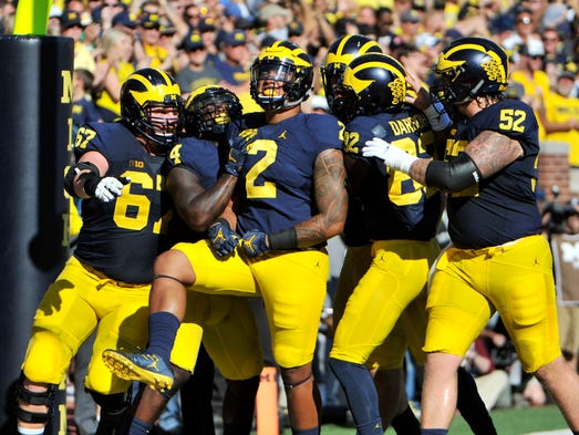 Teammates celebrate with Michigan tight end Devin Asiasi