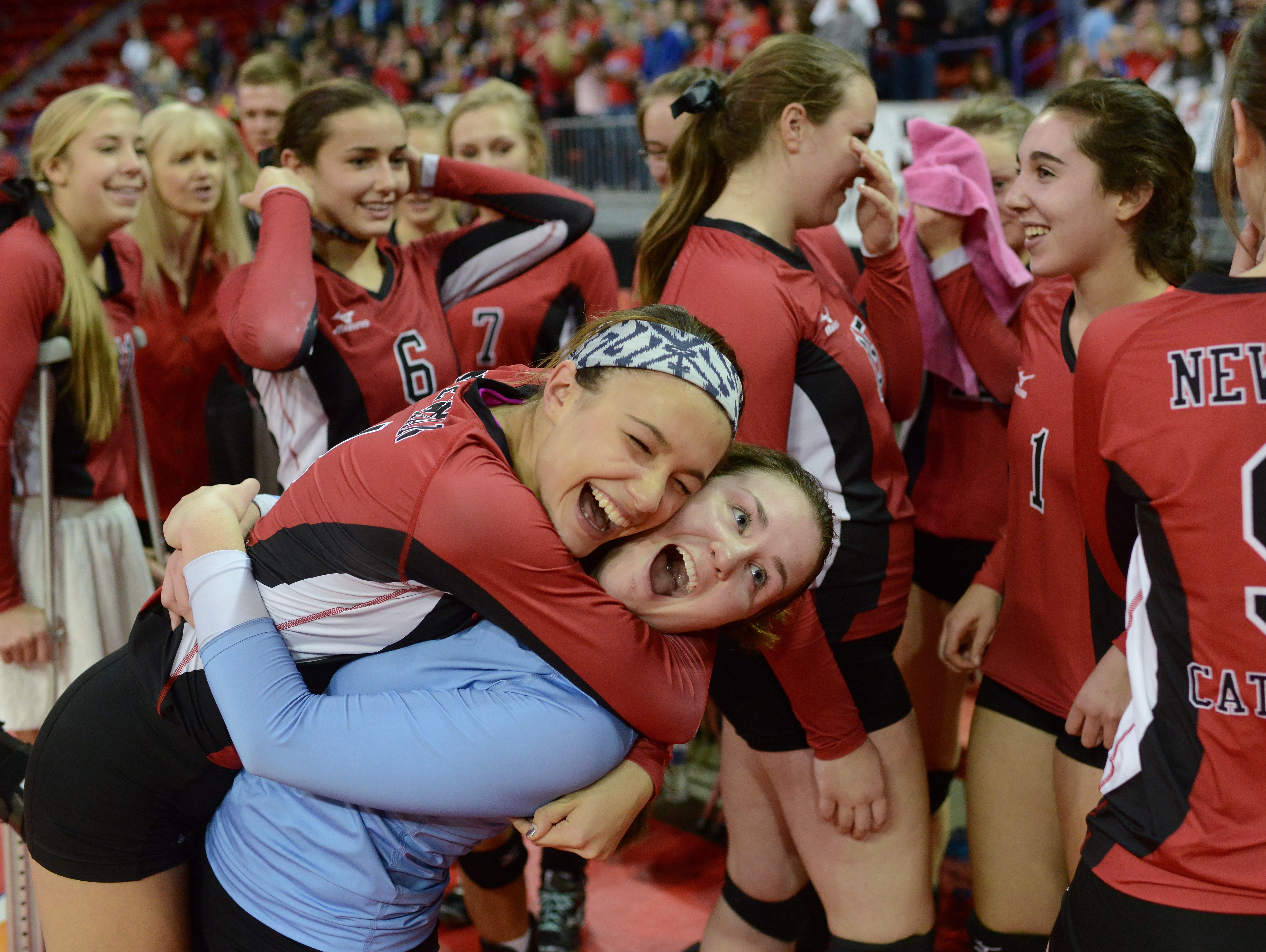 Newman Catholic setter Rylie Vaughn leaps on libero Breck Wcisel as they celebrate their victory in the WIAA Division 4 State Championship volleyball match at the Resch Center in Ashwaubenon Saturday. Newman Catholic defeated Southwestern in four sets.