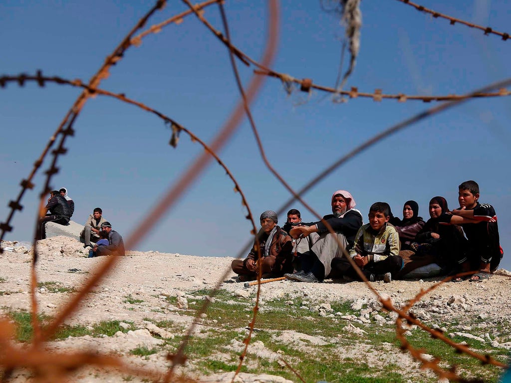 Displaced Iraqis sit near barbed wire as Iraqi government forces supported by fighters from the Abbas Brigade, which fight under the umbrella of the Shiite popular mobilisation units, advance in village of Badush northwest of Mosul during the ongoing
