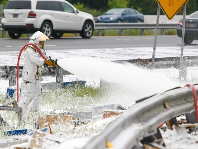 Dominic Pizzo with Station 33 Delaware Air Guard uses foam to spray on the millions of bees along I-95 near Newark, Delaware Wednesday, May 21, 2014.