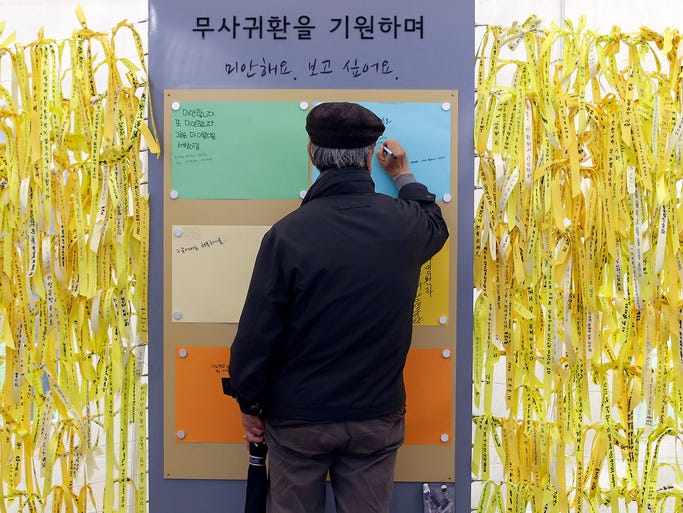 A man writes a message for missing passengers aboard the sunken ferry Sewol at a memorial altar in front of the City Hall in Seoul. The ferry capsized and sank on April 16.
