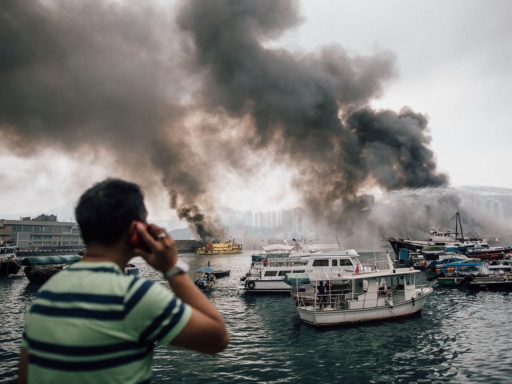 Residents and bystanders watch as firefighters extinguish fires on boats at the Shau Kei Wan typhoon shelter on in Hong Kong. A fire swept through several boats anchored at the Shau Kei Wan typhoon shelter.
