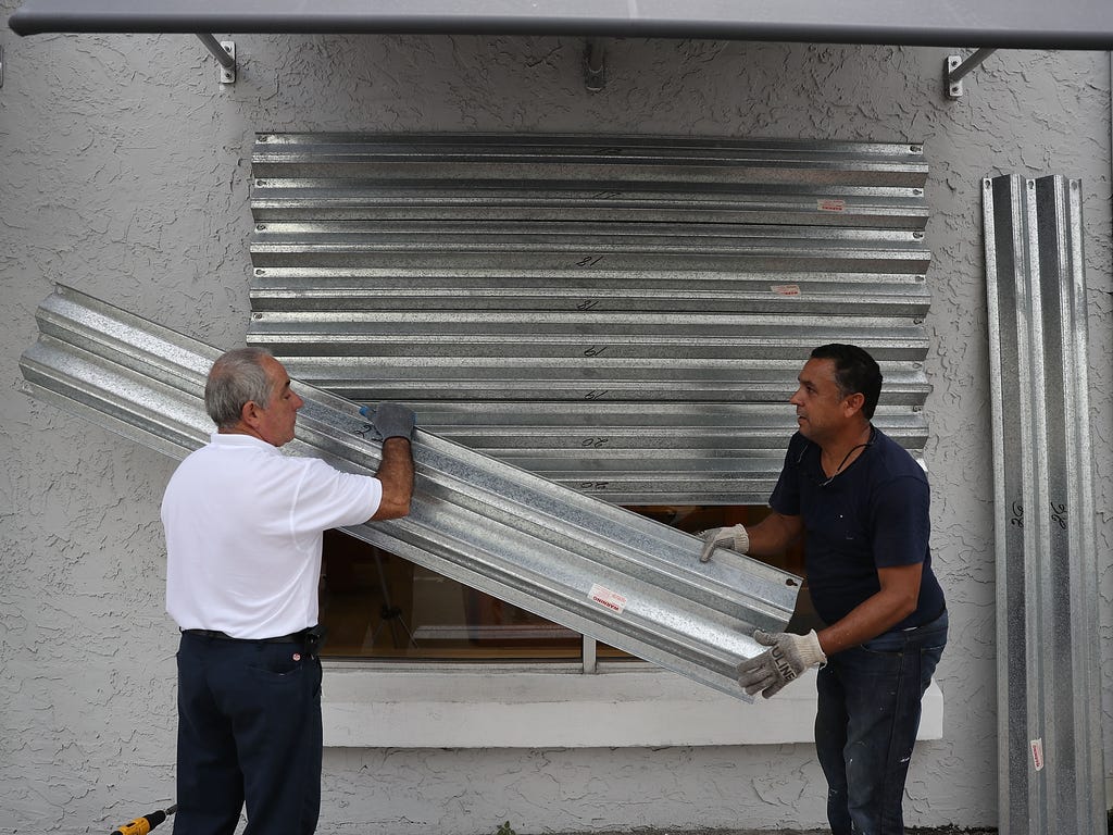 Gus Sousa, left, and Winston Mora put hurricane shutters on a business as they prepare for Hurricane Irma on Sept. 6, 2017, in Miami. It's still too early to know where the direct impact of the hurricane will take place but Florida is in the area of 