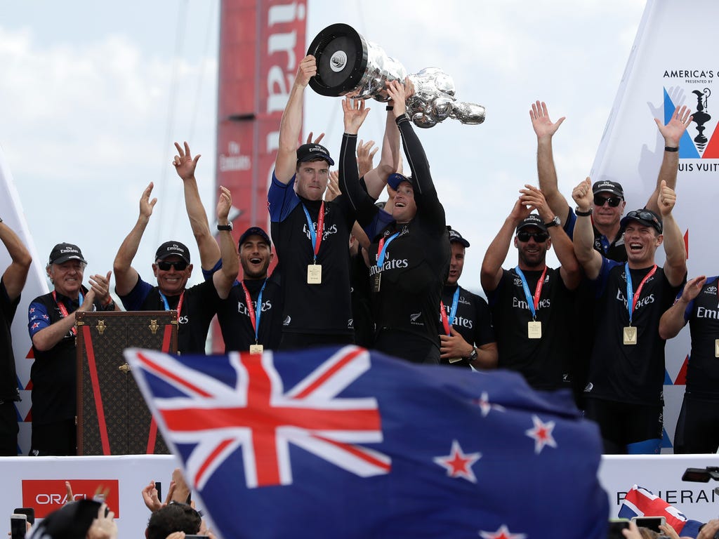 Emirates Team New Zealand helmsman Peter Burling, left, and teammate Glenn Ashby hold the America's Cup aloft as they celebrate with teammates after defeating Oracle Team USA in the America's Cup sailing competition in Hamilton, Bermuda.