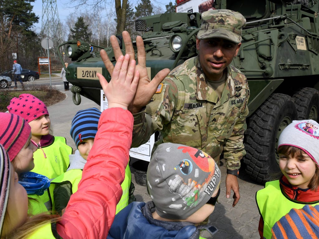 A US soldier gives high five to a child in Warsaw along with troops taking part with a NATO battalion being deployed in the country, part of the alliance's effort to beef up its eastern flank.