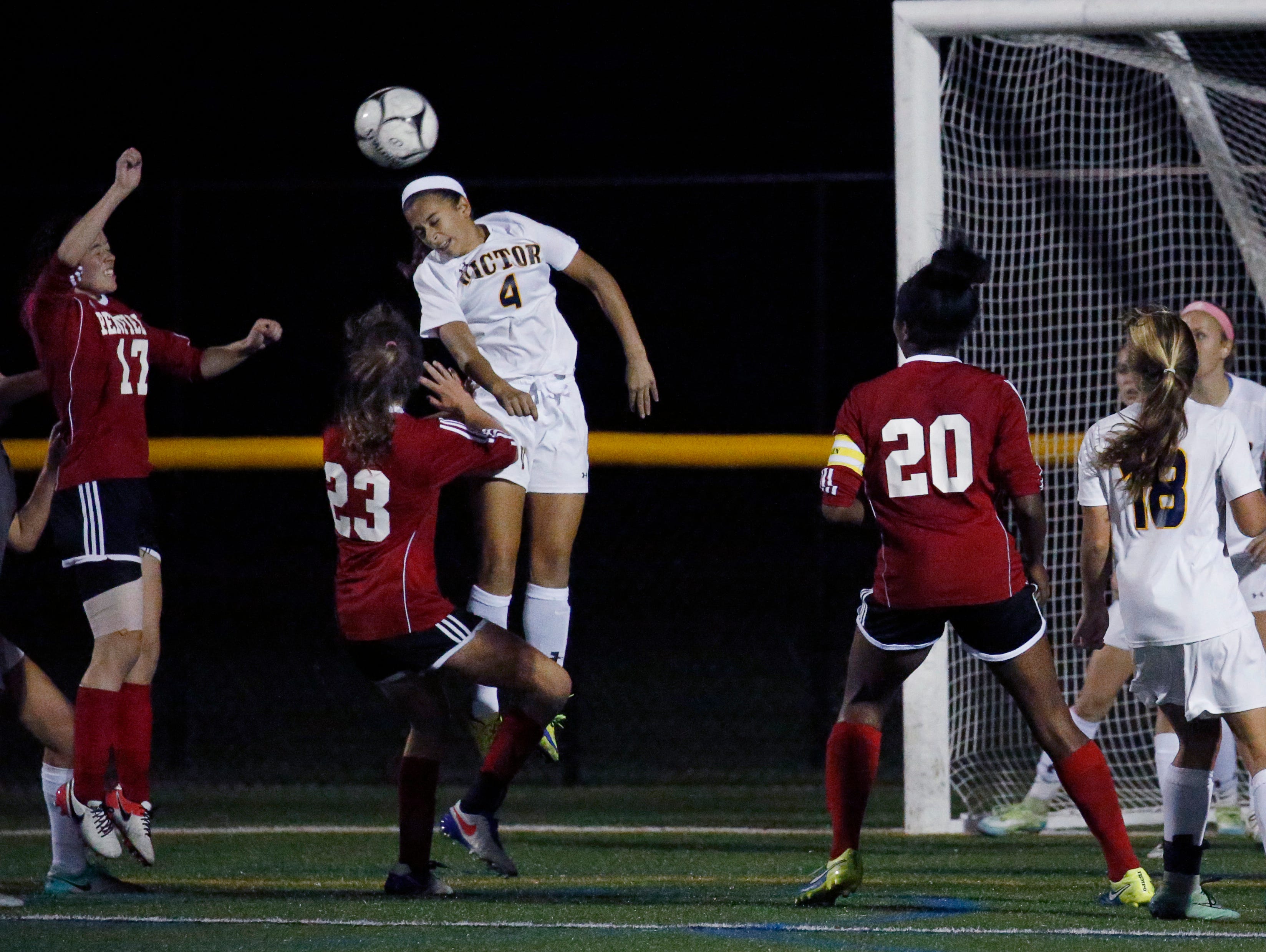 Victor's Olivia Damico jumps for the ball over Penfield players to defend the goal in the first half at Webster Schroeder High School.