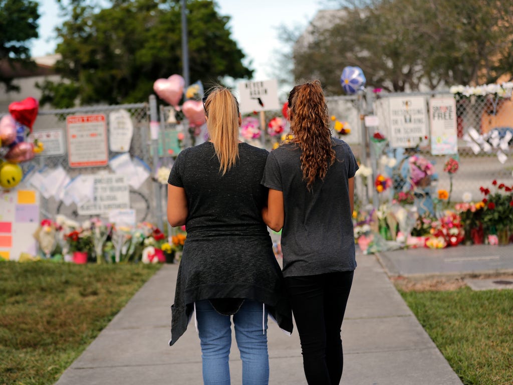 Sara Smith, left, and her daughter Karina Smith visit a makeshift memorial outside the Marjory Stoneman Douglas High School, where 17 students and faculty were killed in a mass shooting on Wednesday, in Parkland, Fla., Feb. 19, 2018. Nikolas Cruz, a 