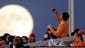 A fan takes a photo of the full moon in the third inning