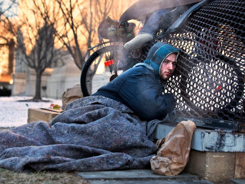 Nick warms himself on a steam grate with three other homeless men by the Federal Trade Commission, just blocks from the Capitol, during frigid temperatures in Washington on Jan. 4, 2014.