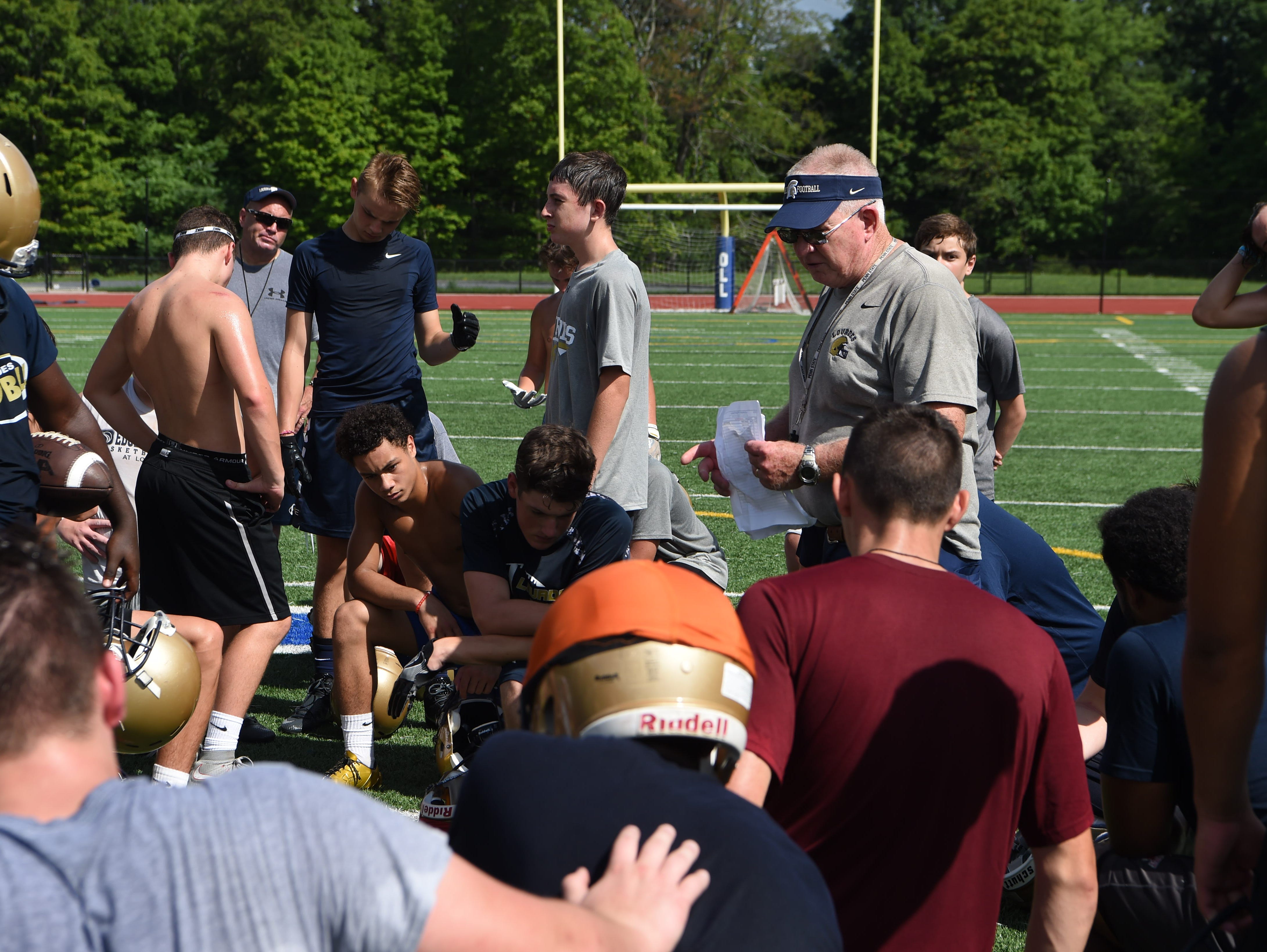 Brian Walsh, center, head coach for Our Lady of Lourdes High School's football team, talks to players before a break in preseason football practice.