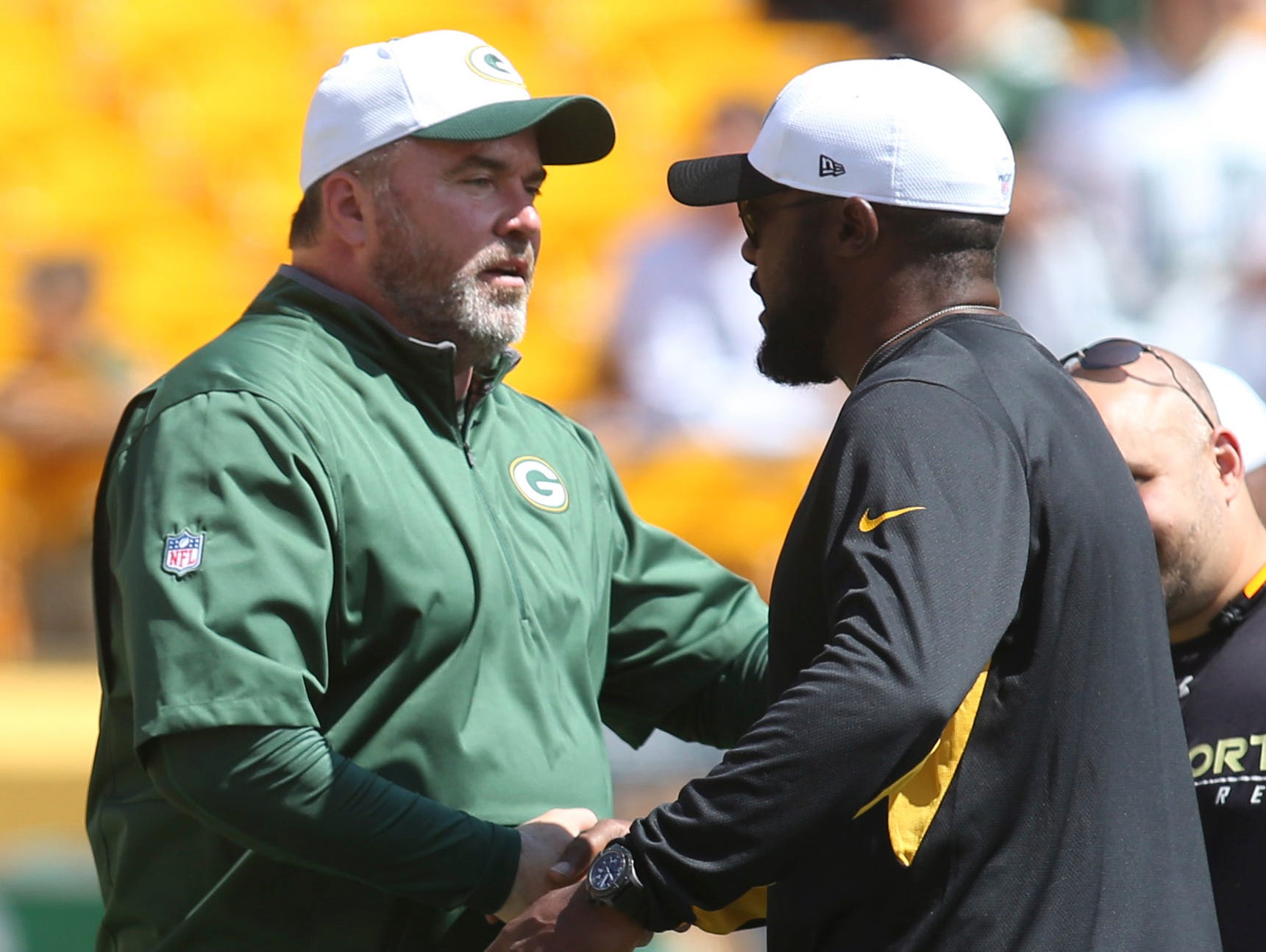 Green Bay Packers head coach Mike McCarthy (L) and Pittsburgh Steelers head coach Mike Tomlin (R) at mid-field before a 2015 preseason game.