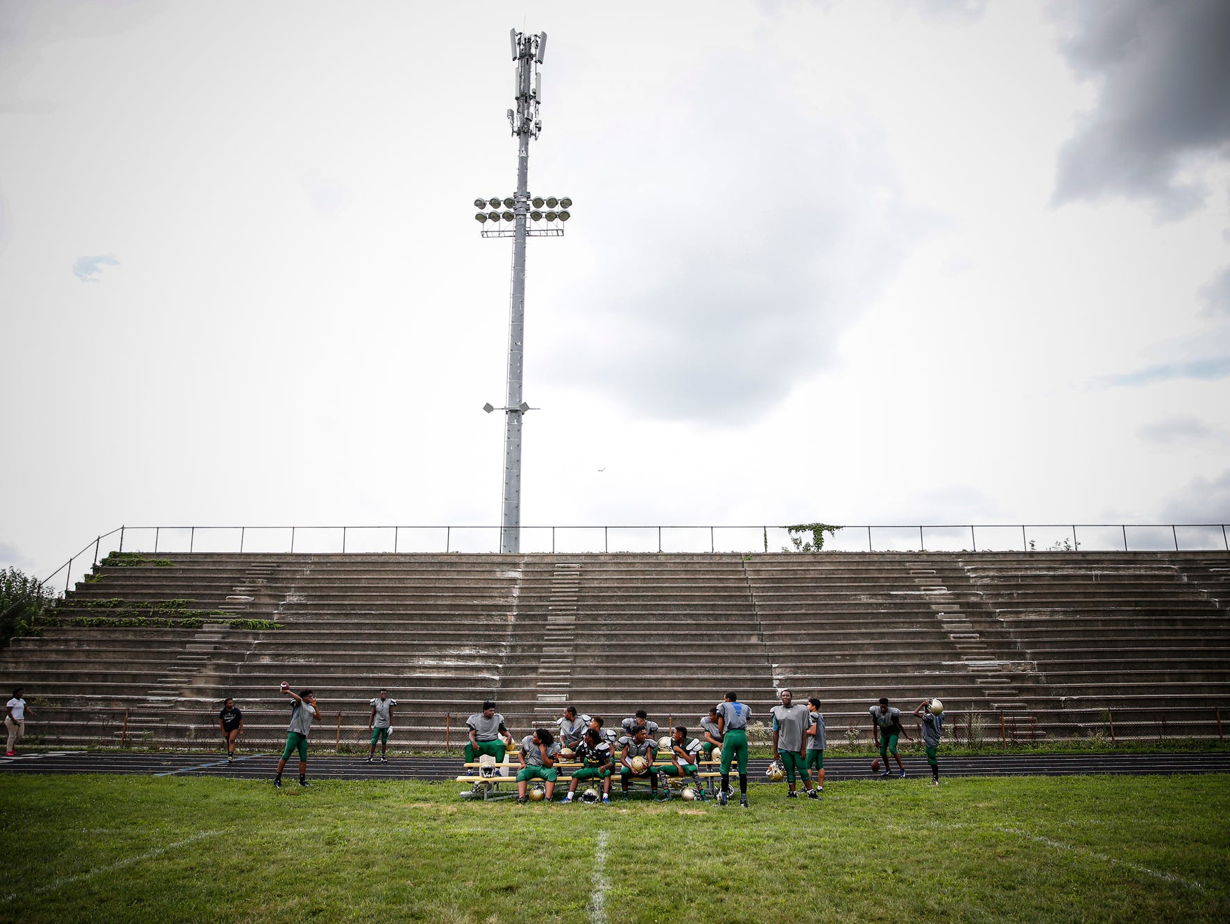 Members of the Crispus Attucks Tigers football team sit on an old set of bleachers to catch a break during practice at Alonzo Watford Athletic Field on Aug. 17, 2016.