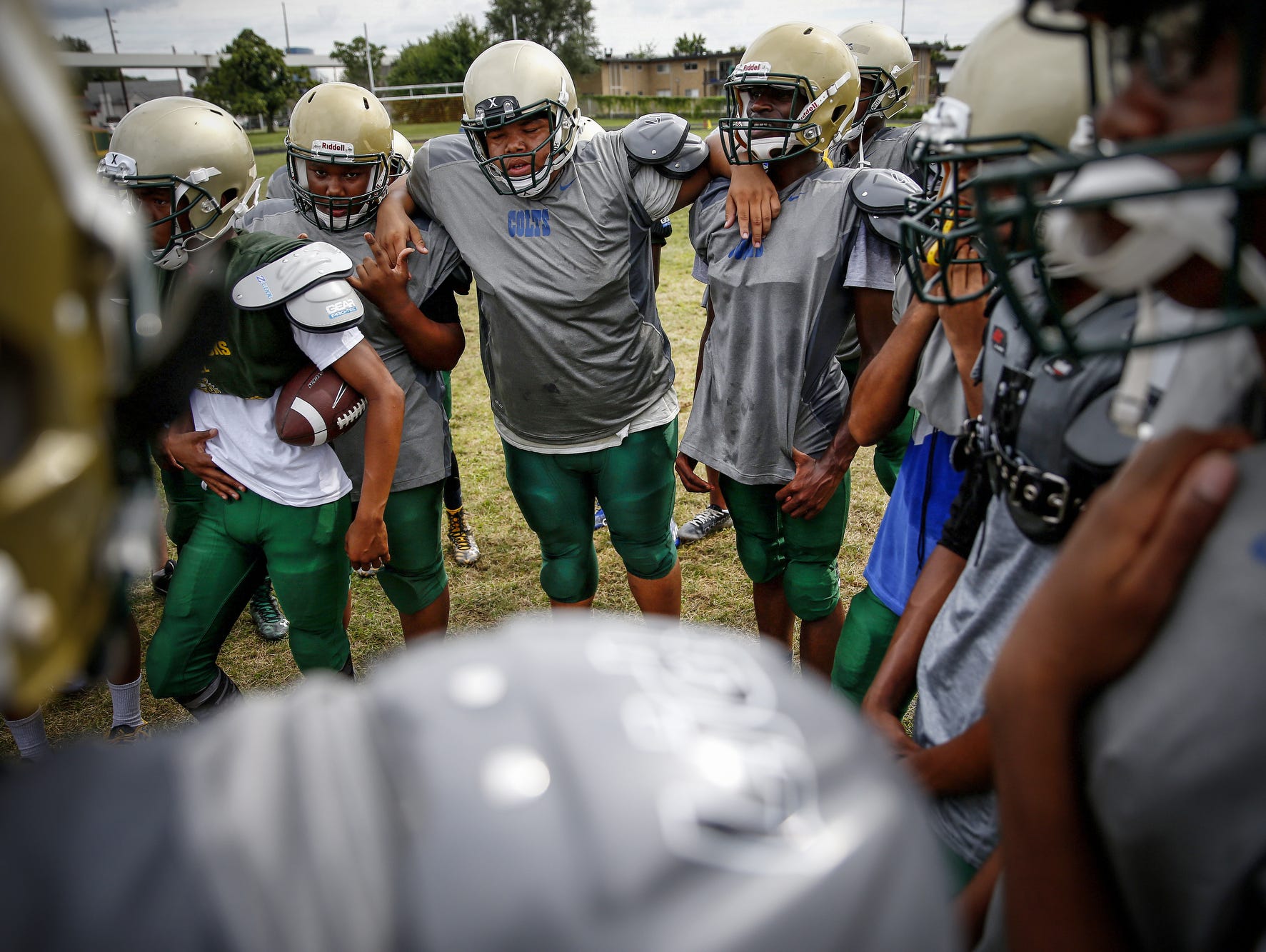 Exhausted Crispus Attucks players lean on each others shoulders during a team huddle during practice at Alonzo Watford Athletic Field on Aug. 17, 2016.