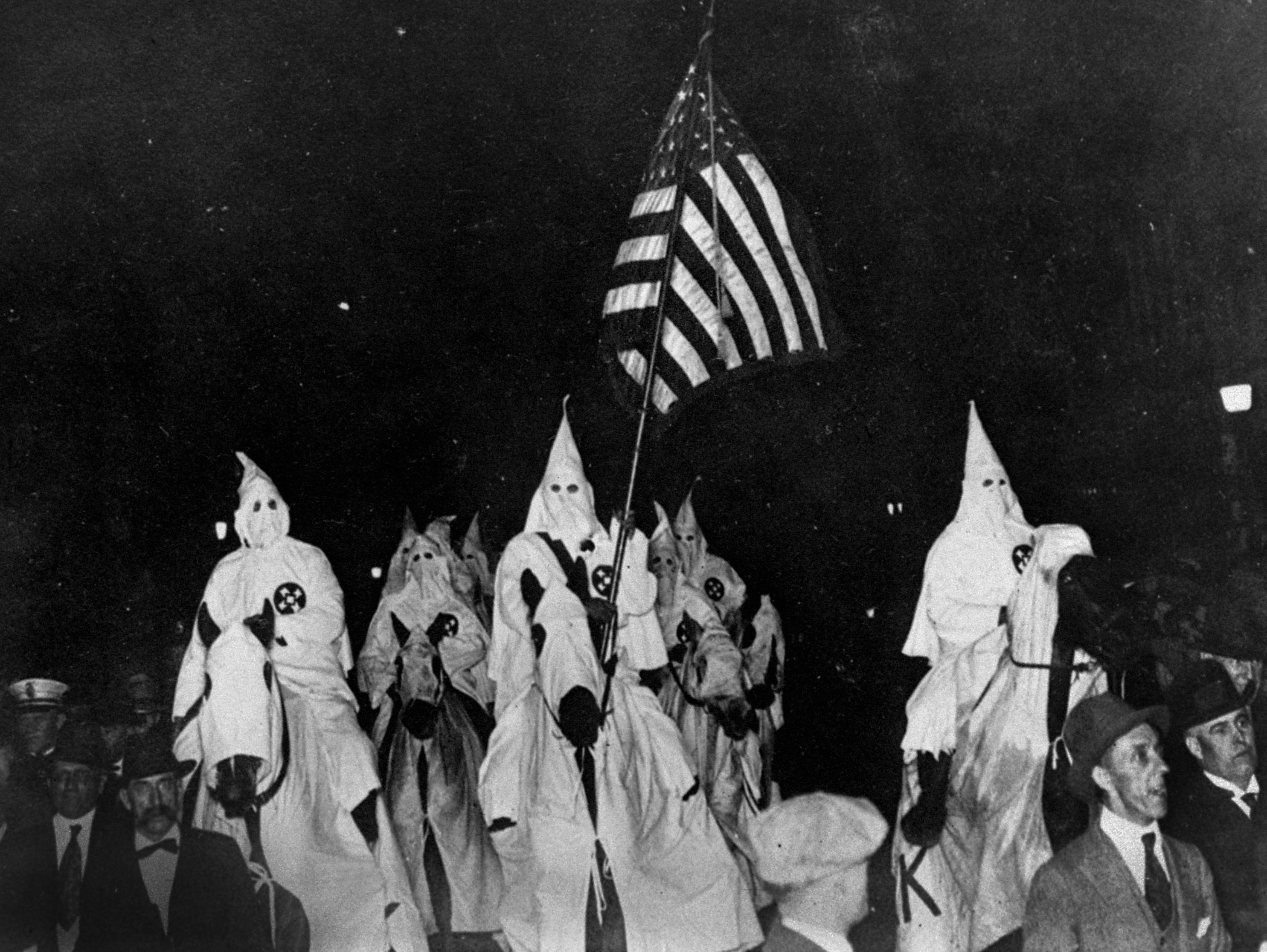 In this 1923 photo, members of the Ku Klux Klan ride horses during a parade through the streets of Tulsa, Okla.