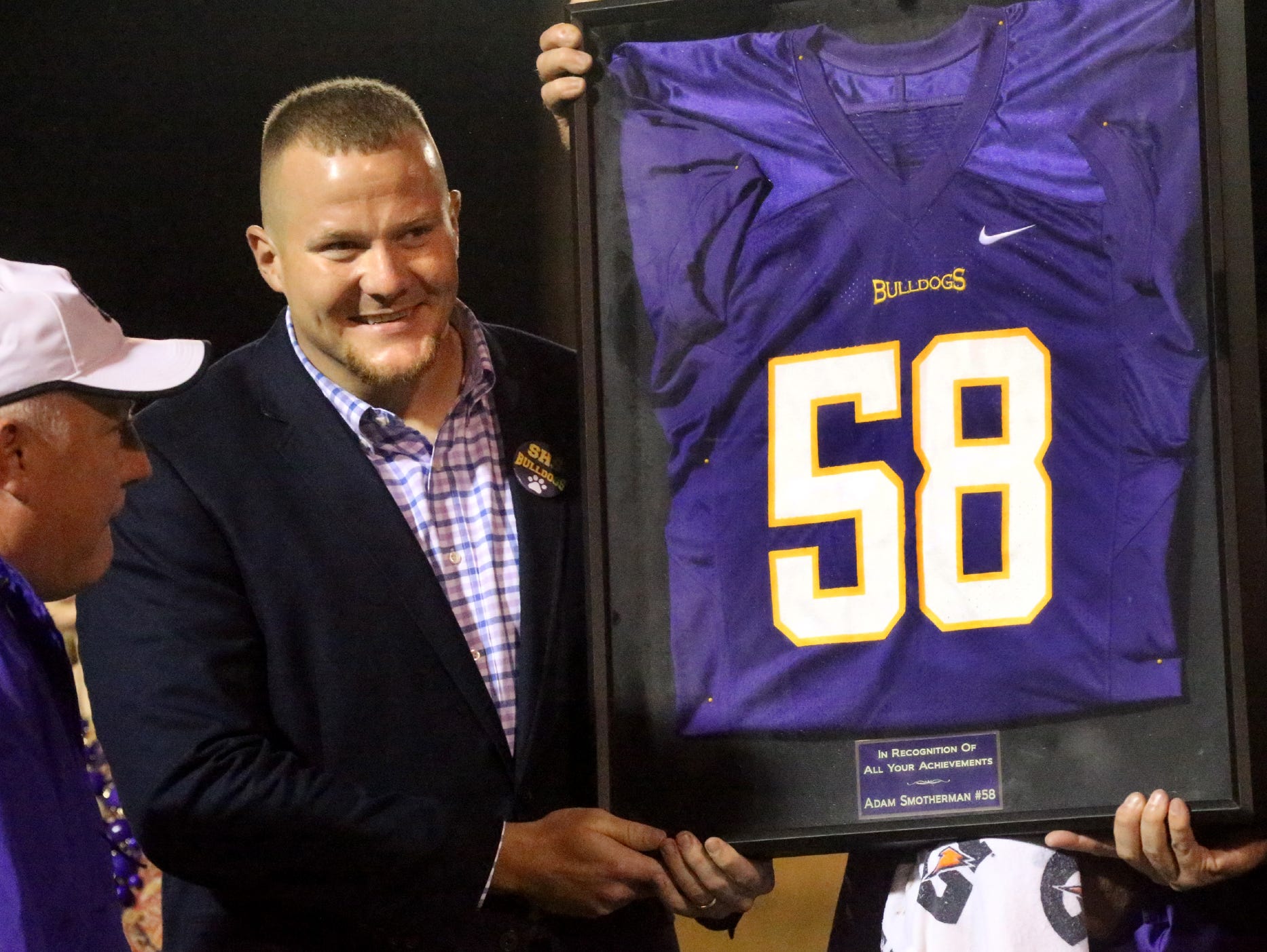 Former Smyrna player Adam Smotherman, right, is presented a framed jersey with his number during half-time of the Smyrna vs. Siegel's game at Smyrna, on Friday Sept. 25, 2015, as Smotherman's number is retired. Former assitant coach Billy Harris, left, to Smotherman congratulates the former player.