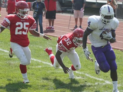 New Rochelle's Keelan Thomas scores a first half touchdown as North Rockland's Michael Cintron and Cameron Lewis follow, during action in their game at North Rockland High School, Sept. 19, 2015.