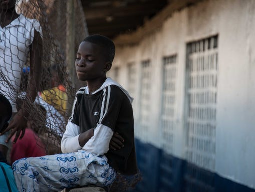Jacob Quasah, 15, peers at his school,  N.V. Massaquoi