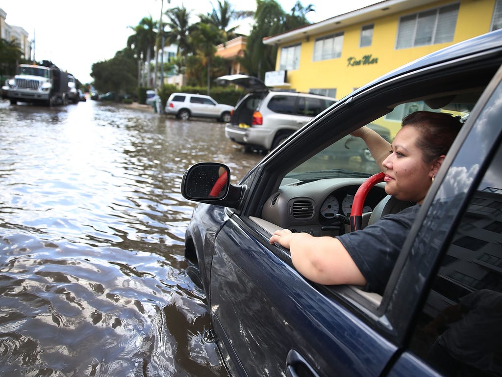 Sandy Garcia sits in her vehicle that is stuck in a flooded street in Fort Lauderdale.