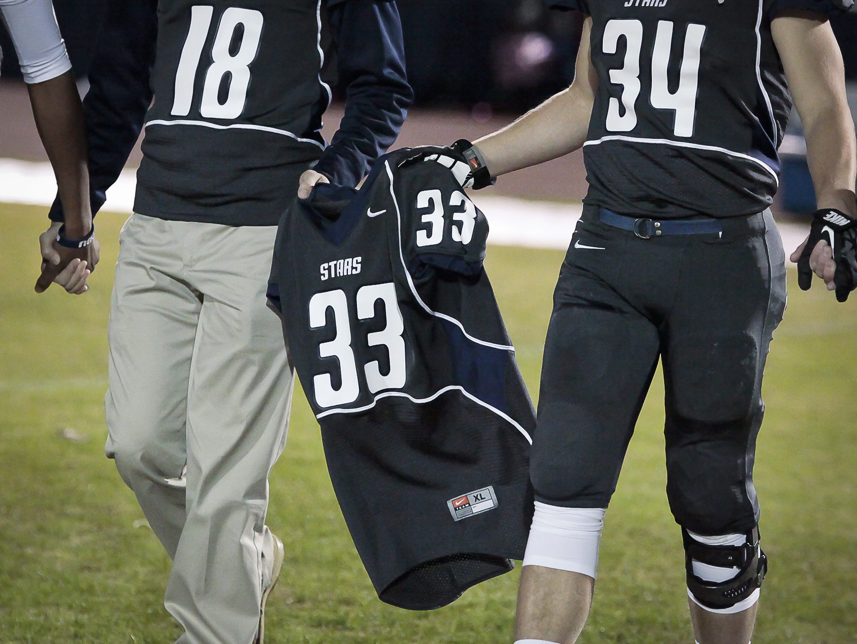 Siegel High School football players carry Baylor Bramble's jersey to the field prior to the Stars' game against Coffee County.