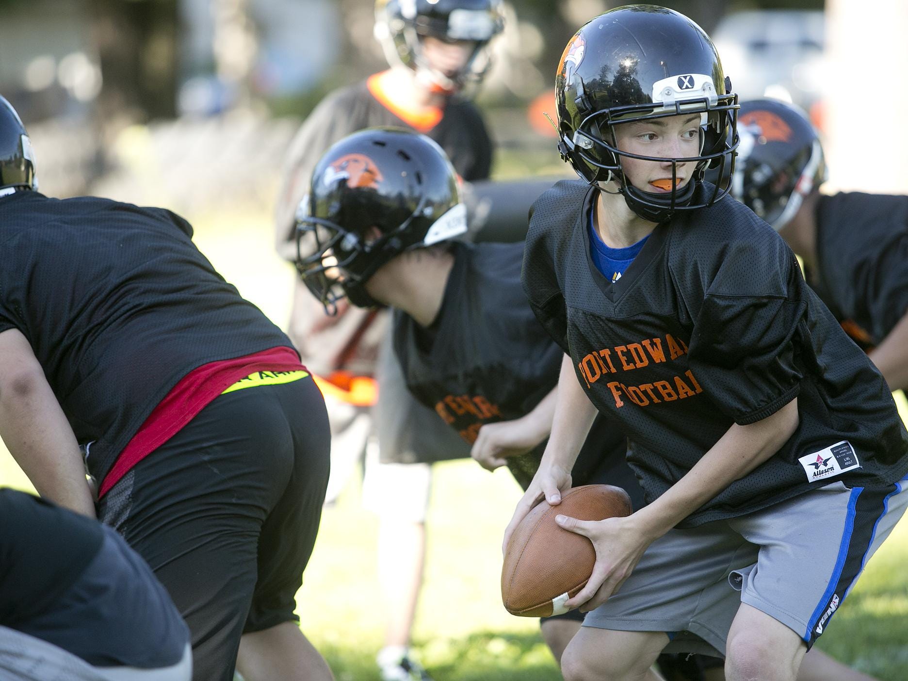 Quarterback Ian Gibbs looks to hand off the ball during the first day of football practice at John Edwards High School, Tuesday, Aug. 4, 2015.