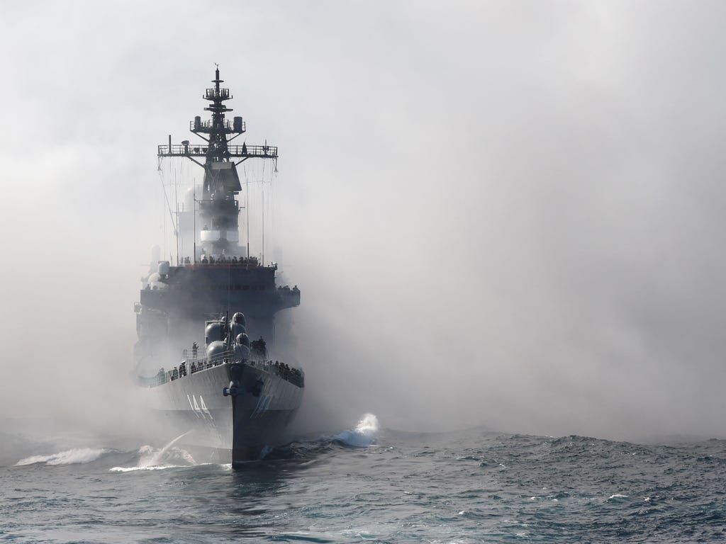 Japan's Maritime Self-Defense Force (MSDF) escort ship Kurama sails through smoke during a fleet review off Sagami Bay, Kanagawa prefecture. Thirty-six MSDF vessels with navy ships from Australia, India, France, South Korea and the United States part