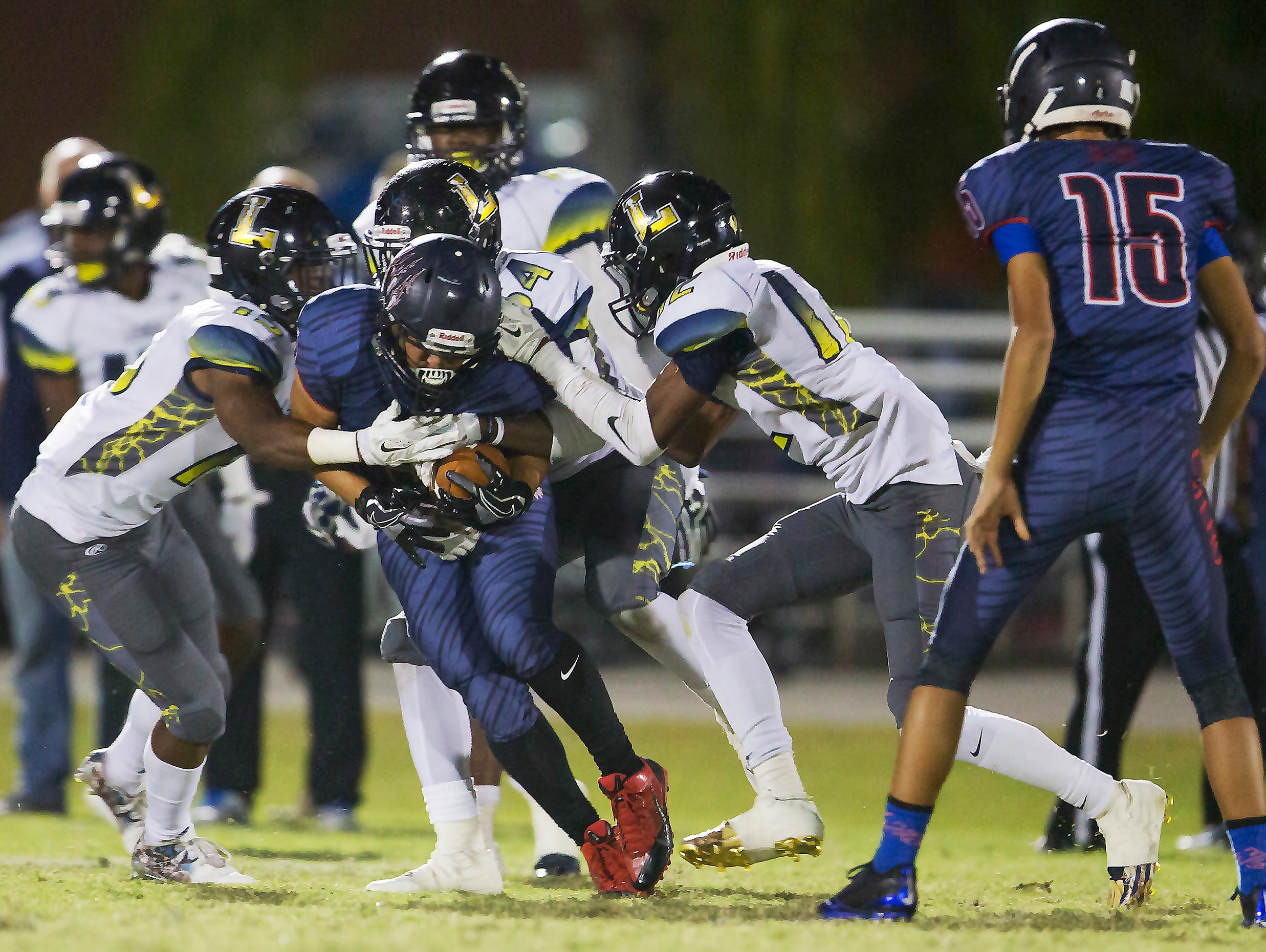 Lehigh Senior High School defenders tackle Estero’s Justin Lopez for a loss during second quarter play on Friday at Estero High School.
