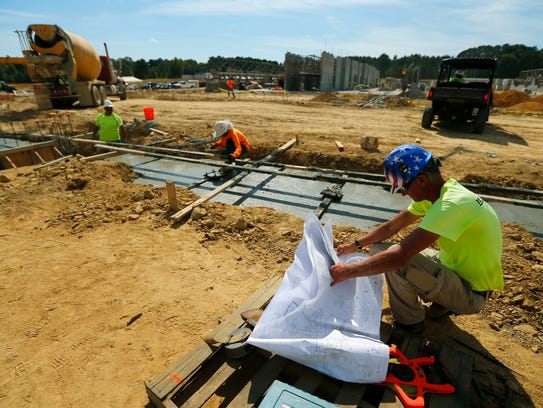 A construction worker looks over plans as a footing