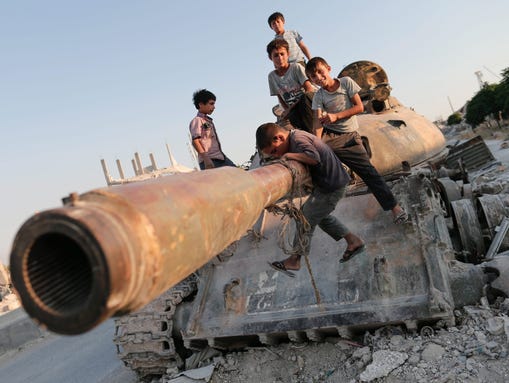 Syrian children play on a destroyed tank  south of