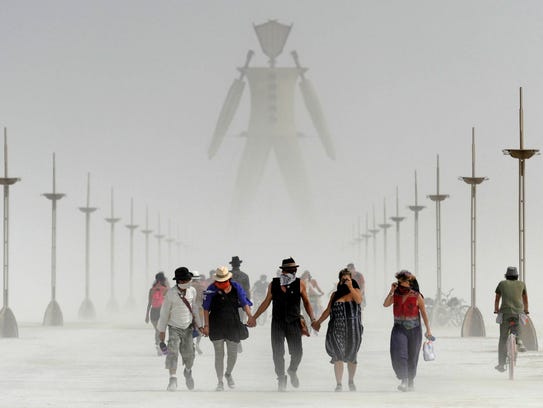 Burning Man participants walk through dust at the annual