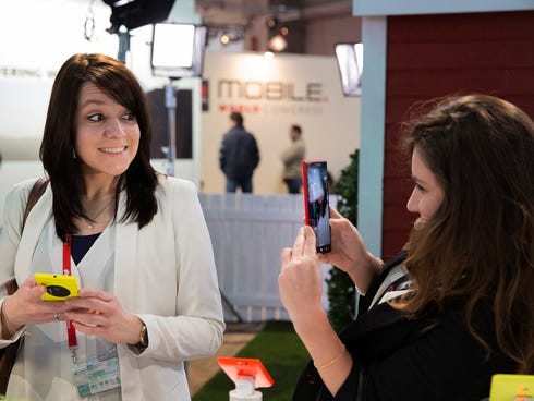 A woman takes a picture with a Nokia Lumia 1520 phone as her friend smiles at the Mobile World Congress in Barcelona, Spain. The latest wave of smartphones will include cameras that closely match higher-end rivals.