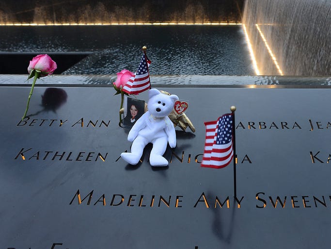 Flags and a stuffed animal are left for victims at the North Tower Memorial Pool at the World Trade Center.