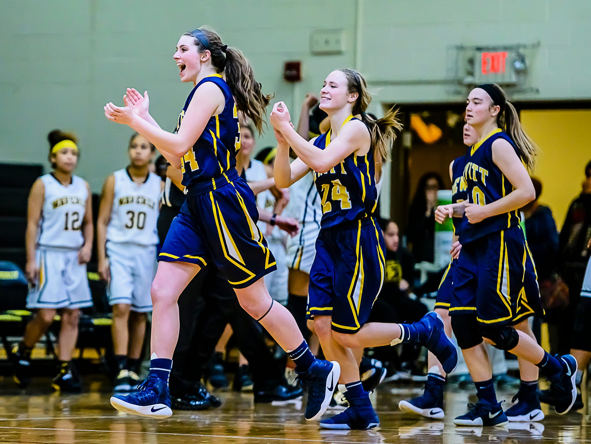 Grace George ,left, and Annie McIntosh ,center, of DeWitt celebrate as they run off the court after their win over Waverly Friday February 10, 2017 in Delta Township. KEVIN W. FOWLER PHOTO