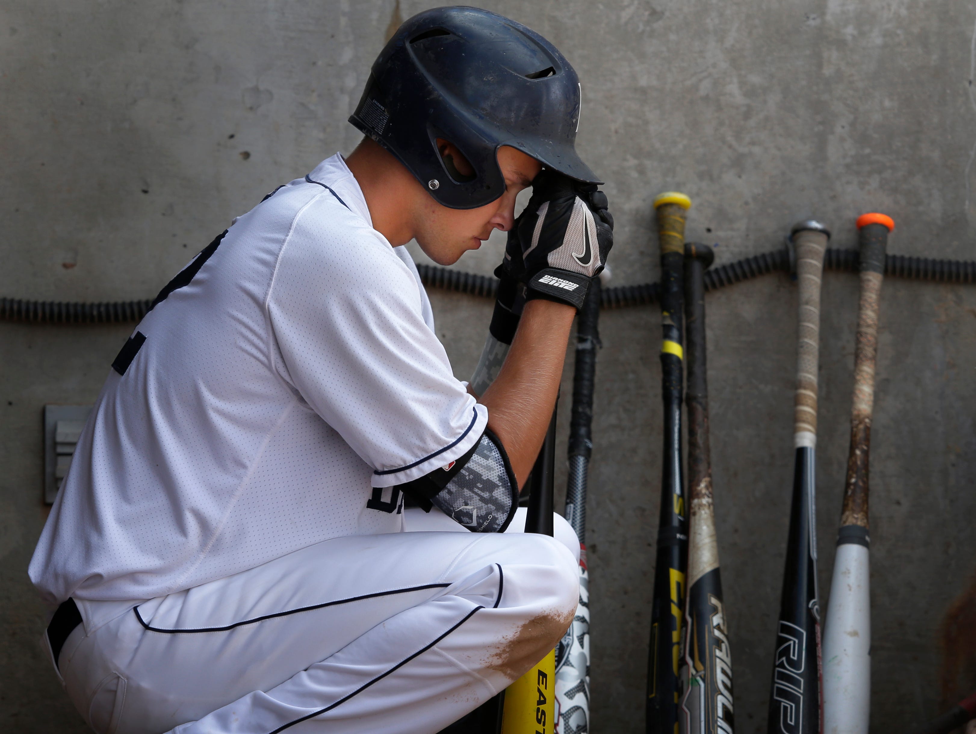 Bay Port's Zach Abfall sits alone in the dugout in the closing moments of a 1-0 loss against Oconomowoc in a WIAA Division 1 state baseball quarterfinal game Tuesday at Neuroscience Group Field at Fox Cities Stadium in Grand Chute.