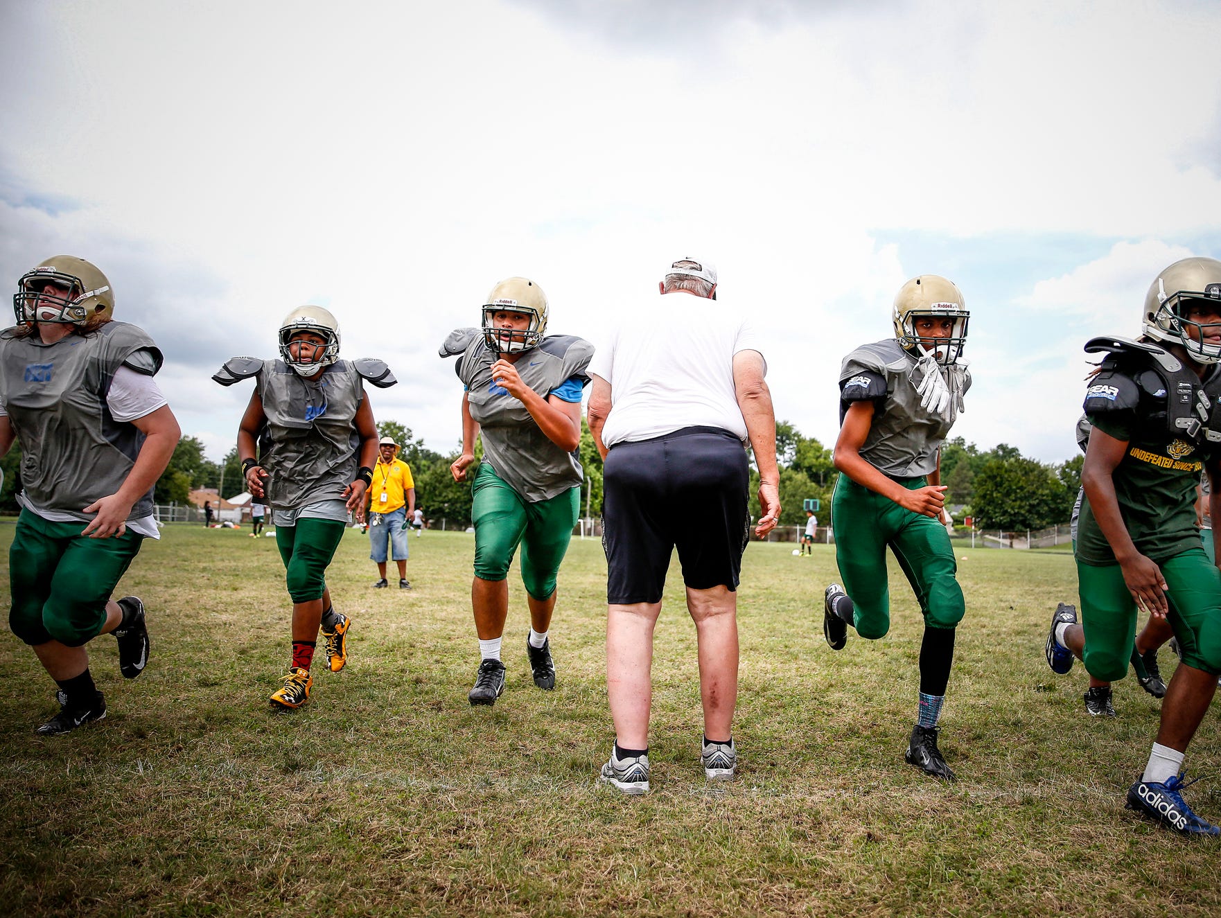 Crispus Attucks assistant coach Bob Ashford gets the team started with sprints during practice at Alonzo Watford Athletic Field on Aug. 17, 2016.