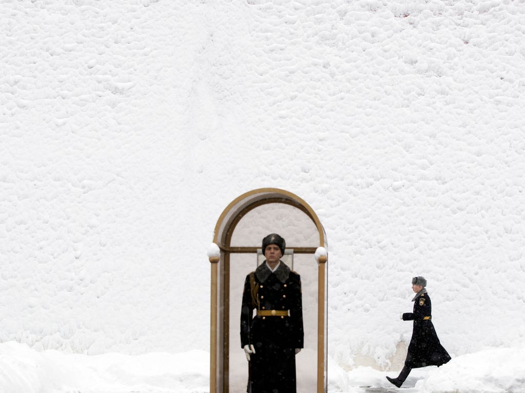 An Honor guard soldier walks along the Kremlin wall as his fellow soldier stands at the Tomb of Unknown Soldier in Moscow, Russia. According to forecasts snowfalls and blizzard will continue in Moscow through the next several days with temperatures d