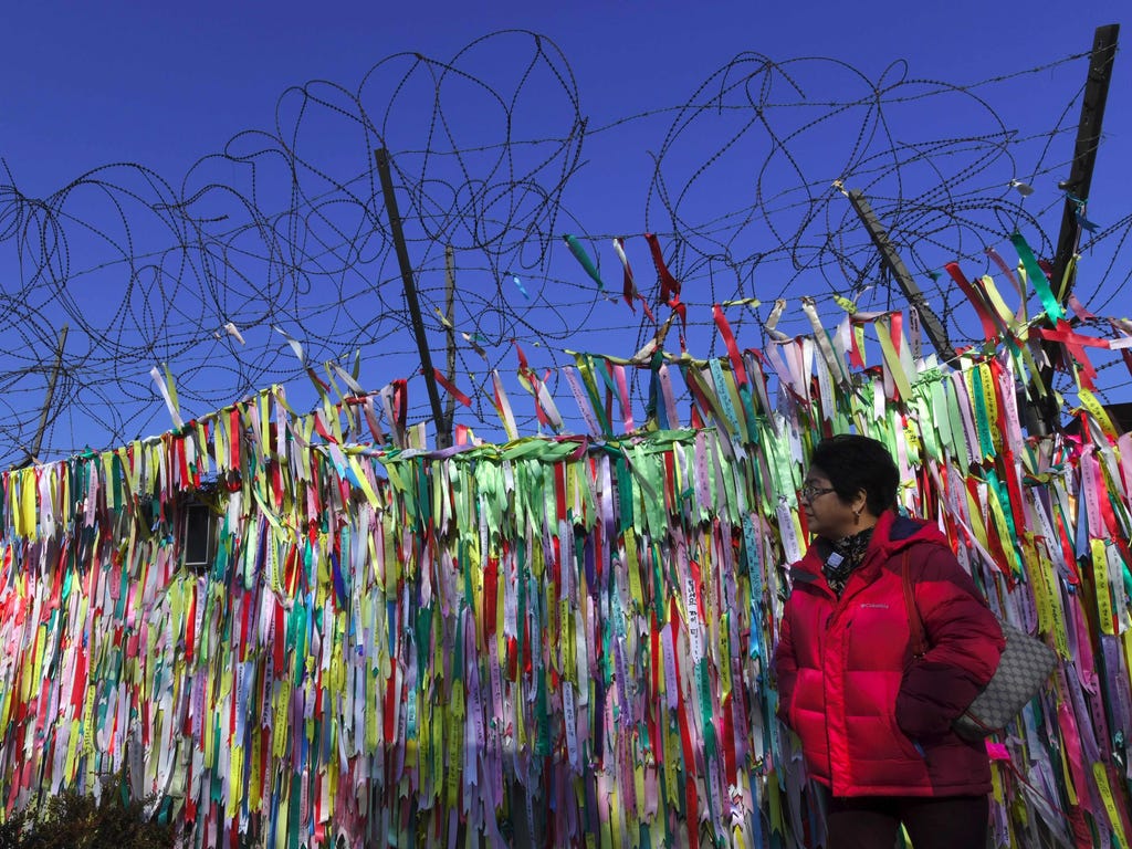 A woman walks past a military fence covered with ribbons calling for peace and reunification at the Imjingak peace park near the Demilitarized Zone dividing the two Koreas in the border city of Paju on Jan. 1, 2018. Kim Jong-Un vowed North Korea woul