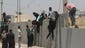 Palestinians climb a wall over as they try to cross into Egypt at the border between the Gaza Strip and Egypt in Rafah.