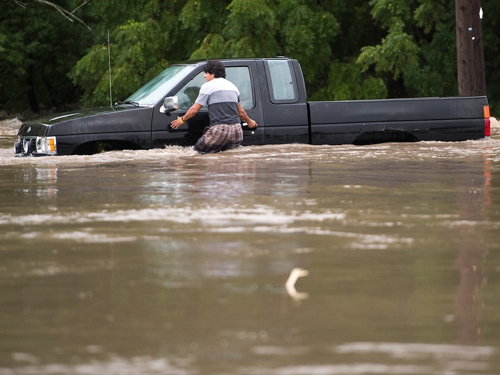A man tries to get back into a vehicle to have it pulled out after it got stuck in high water in South Kansas City, Mo. Overnight storms with heavy rains led to major flooding across the Kansas City area.